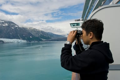 cruise passenger views coast through binoculars