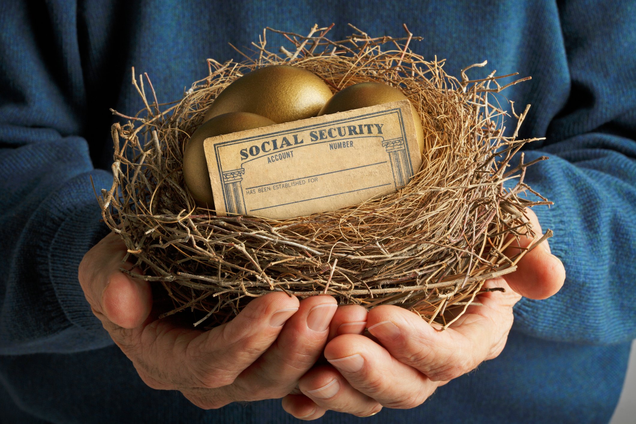 Hands holding a nest with golden eggs and Social Security card.