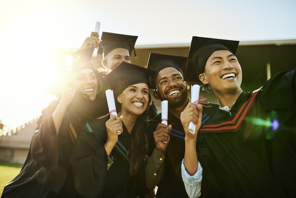 Group of college graduates holding diplomas. 