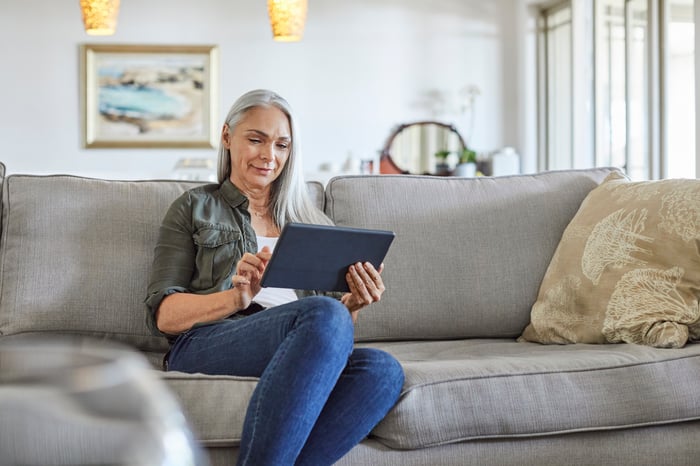 A person sitting on a couch holding a tablet.