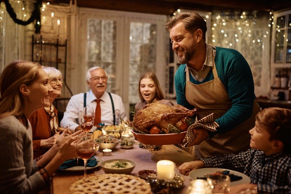 Man carrying a turkey at a Thanksgiving dinner.