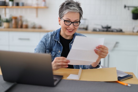 A retired woman reviewing a paper document while seated.