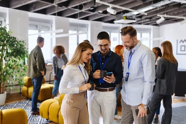 coworkers gather around worker with smartphone