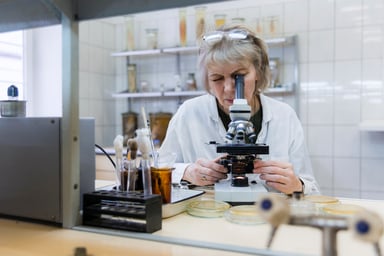 scientist peers into microscope in lab