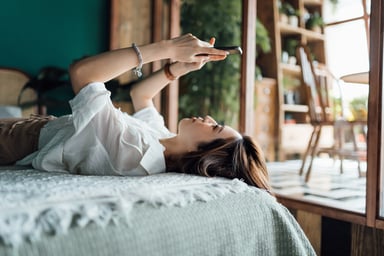 Person laying on a bed using a smartphone