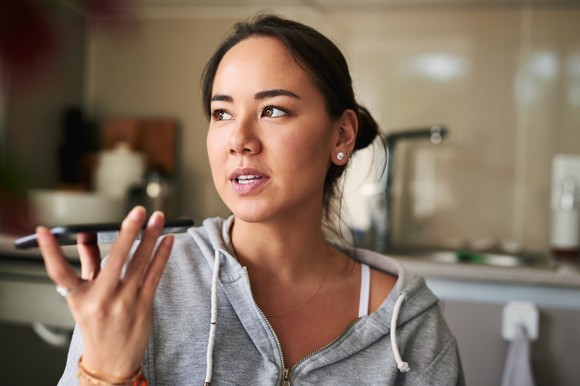 A person uses a voice assistant on a smartphone.