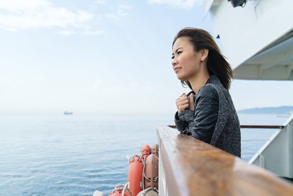 Woman looking out to sea on cruise deck. 