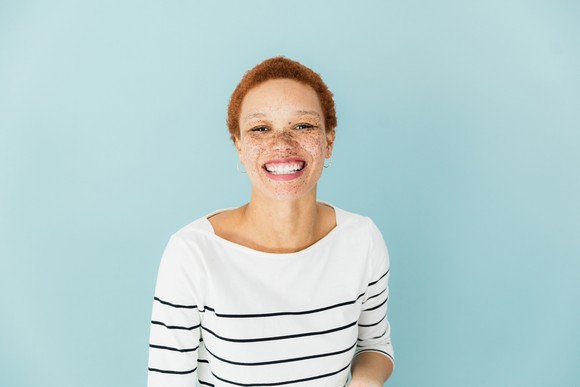 Someone in a sweater is smiling broadly. 