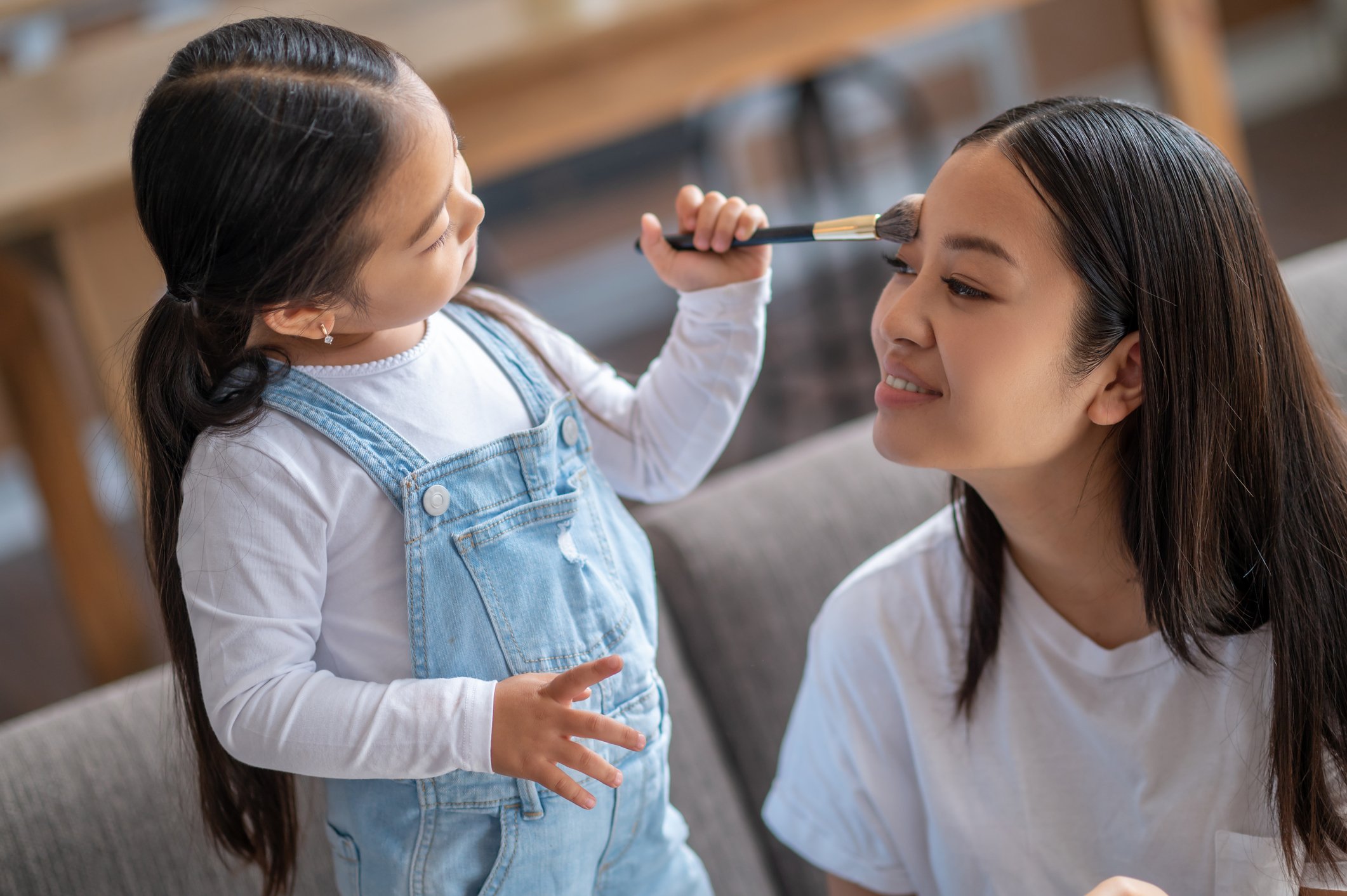 A child putting blush on a woman's face