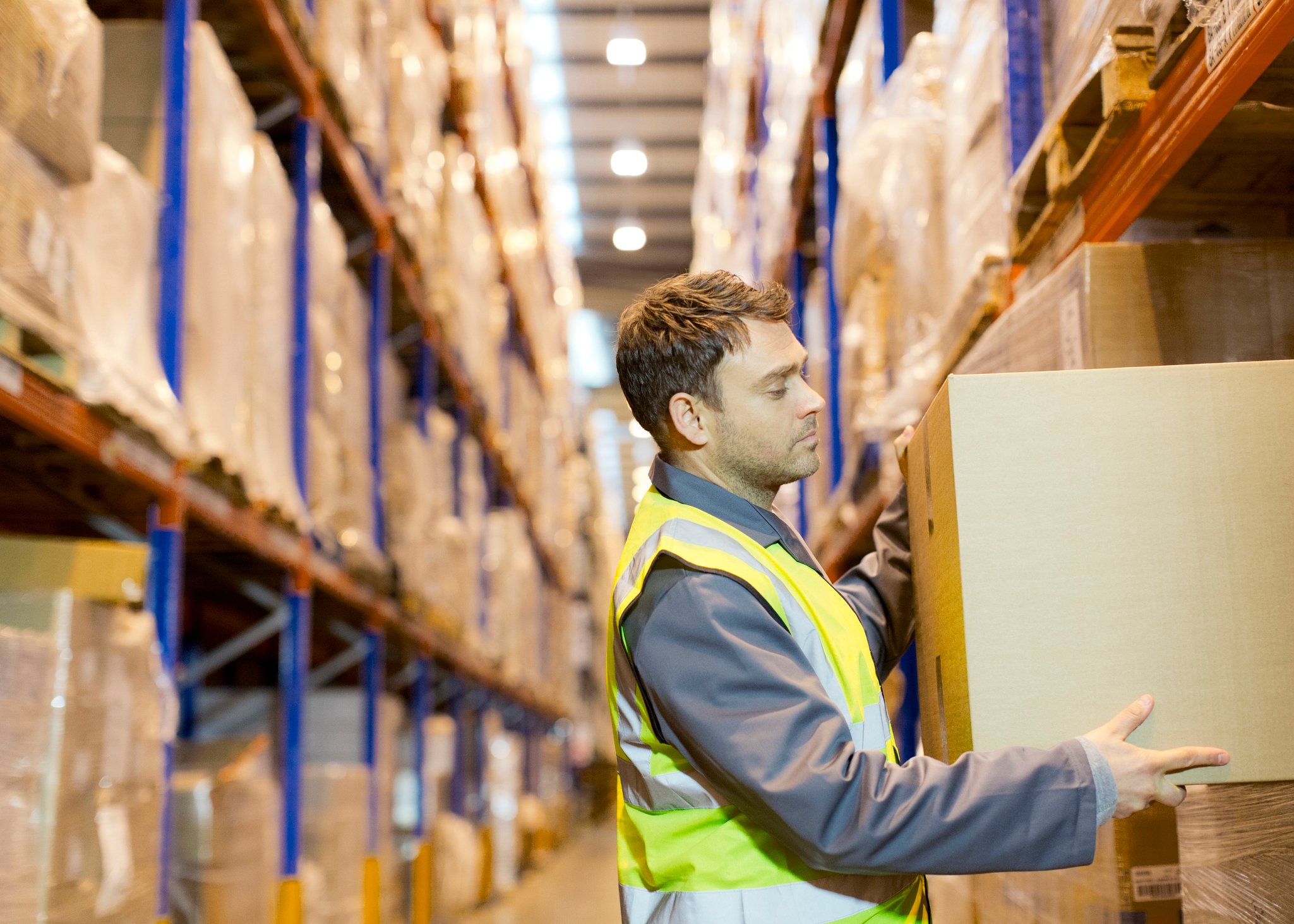 A person lifting a box in a warehouse.