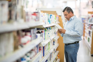 Person reading a product label at a pharmacy.
