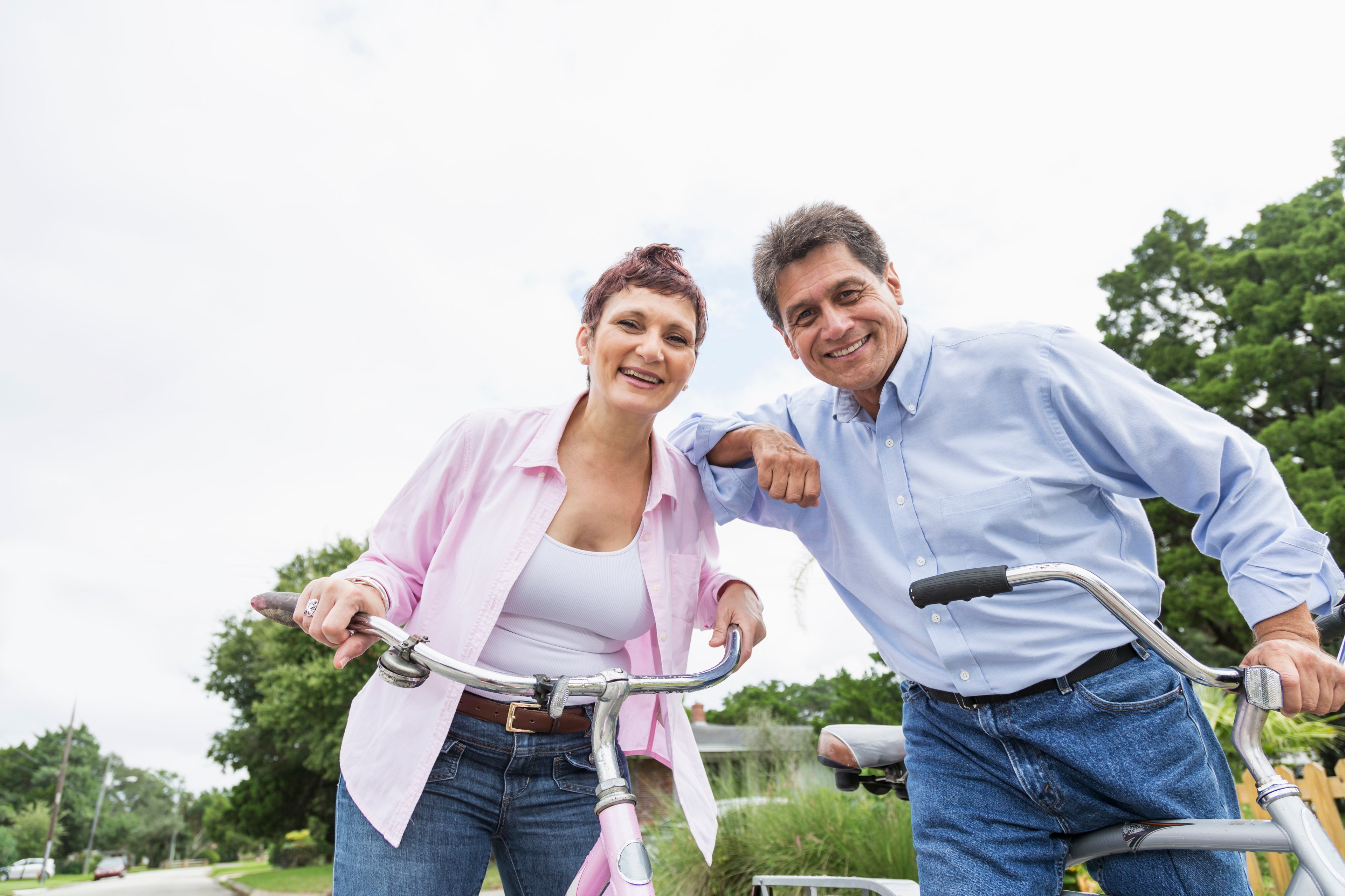Two people standing still on bikes and leaning against each other.