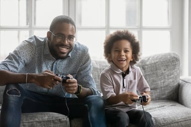 adult and child playing video games on the couch