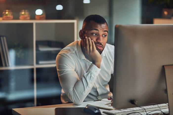Person with a confused expression looking at a computer.