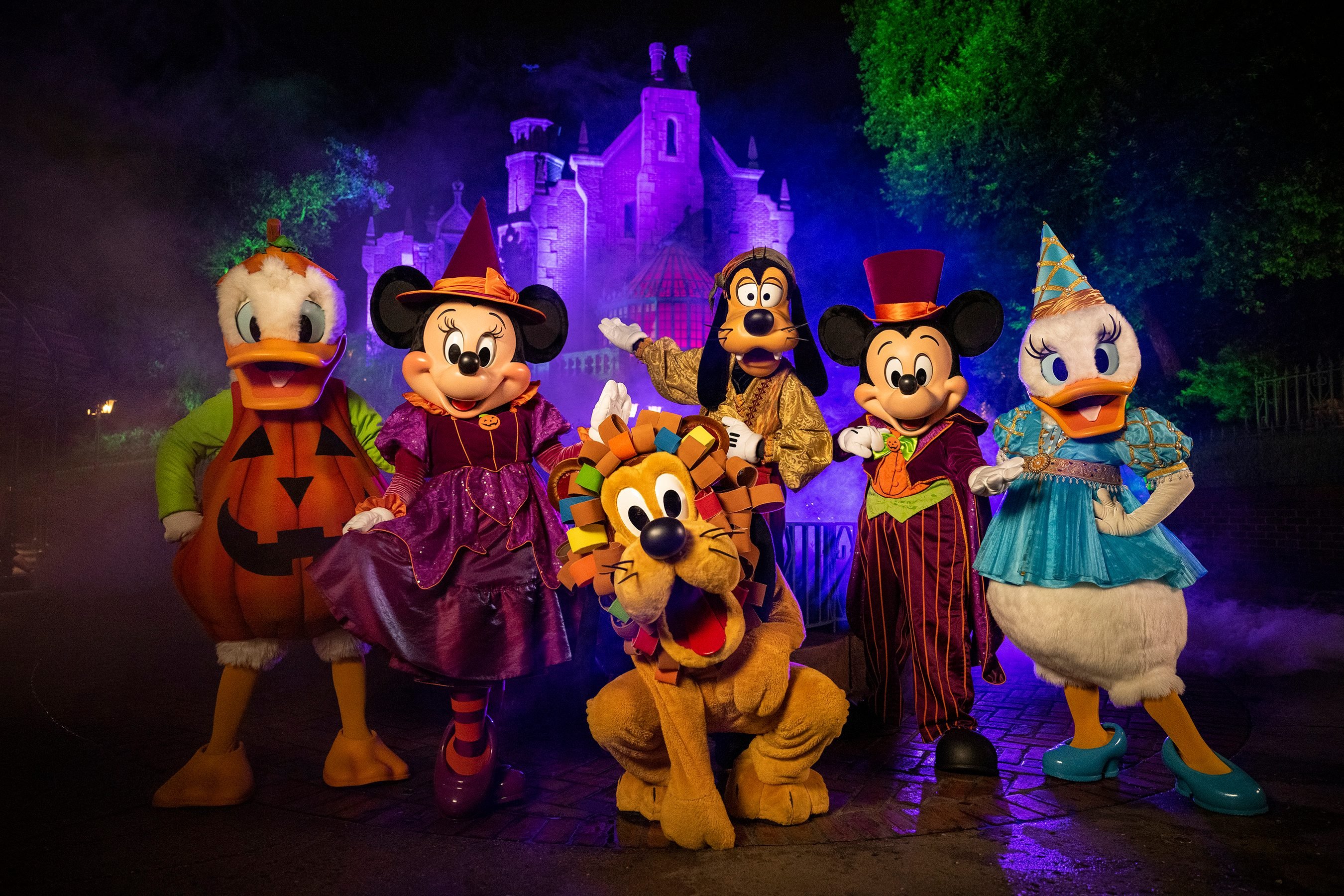 Disney characters dressed up for Halloween in front of the Haunted Mansion.