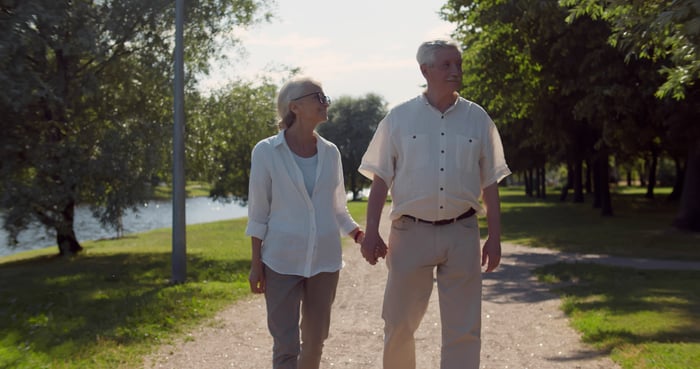 Two people walking and holding hands outdoors.