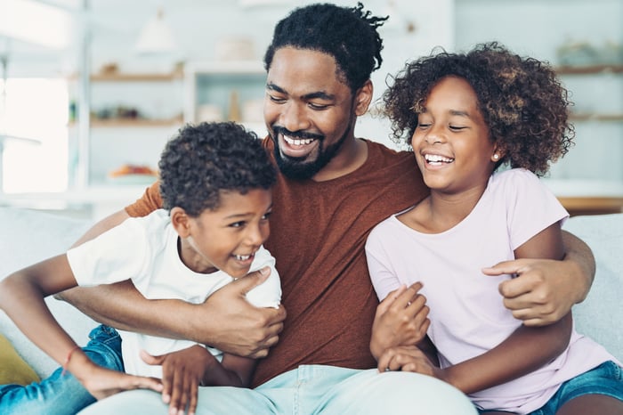 Smiling parent hugging two children.