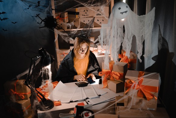 Person in Halloween costume working with a calculator.