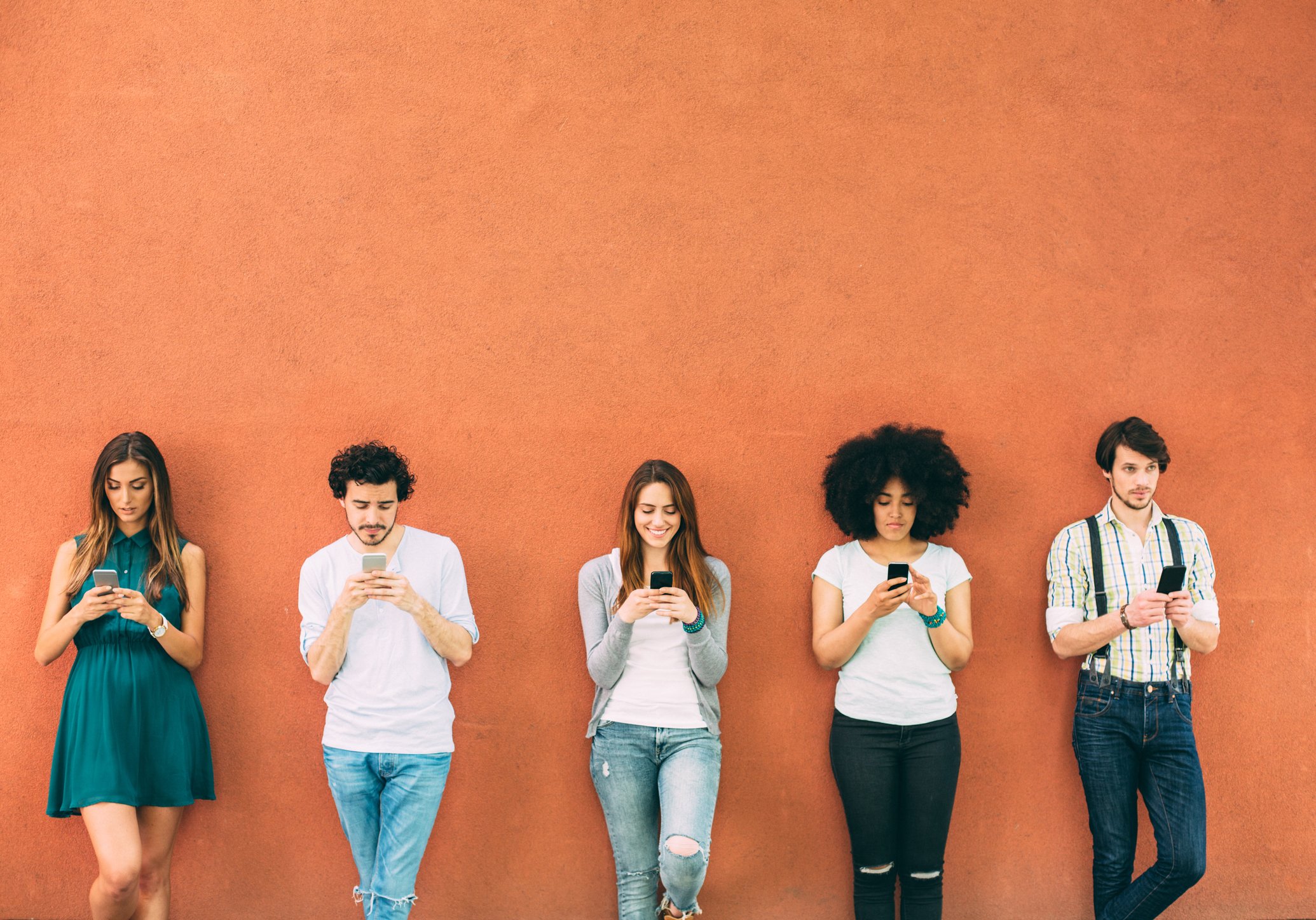 Five friends use smartphones outside.