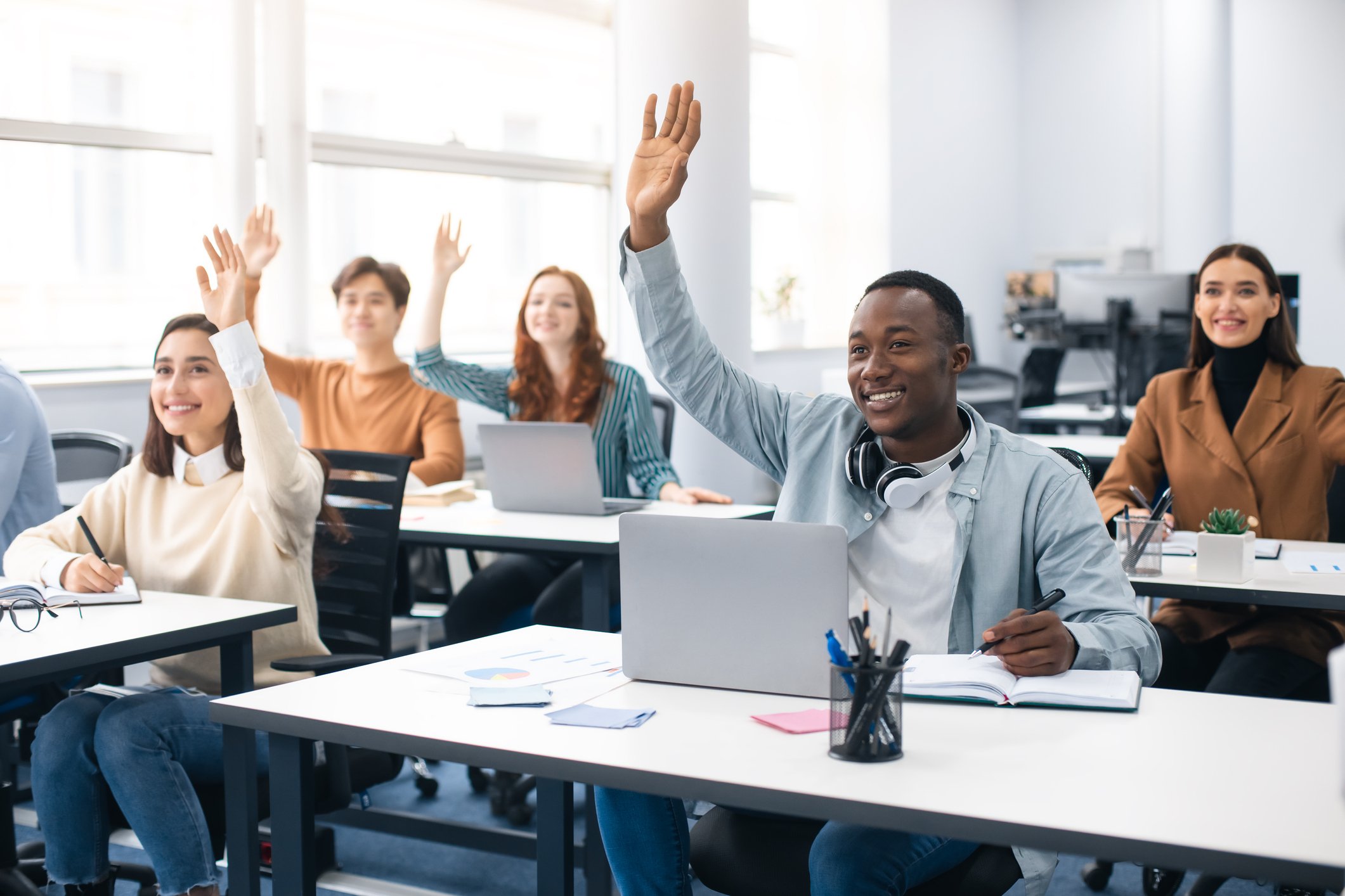 Student raising his hand in a classroom.