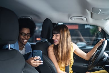 Two people in a car looking at a phone