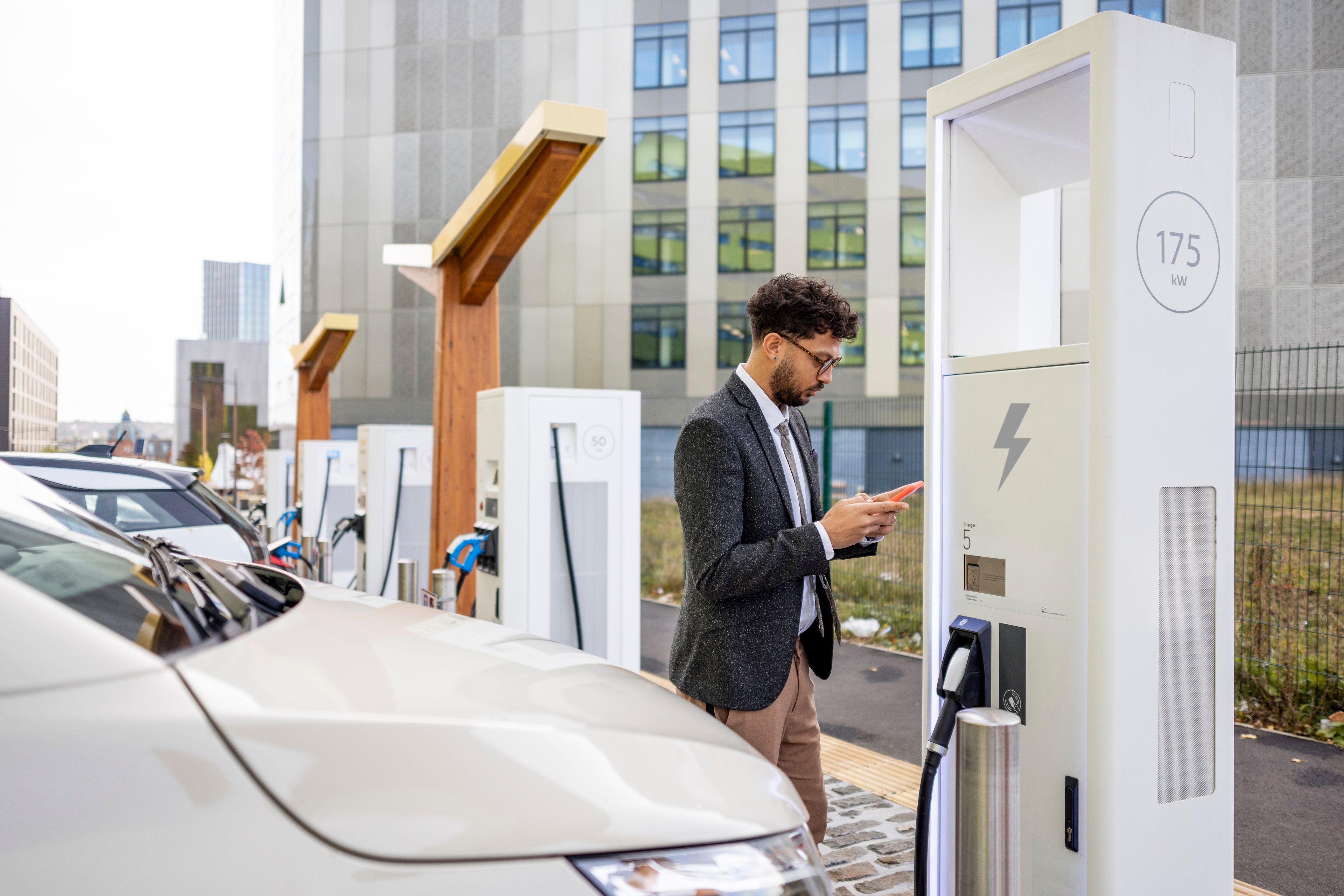Person standing by electric car and charger