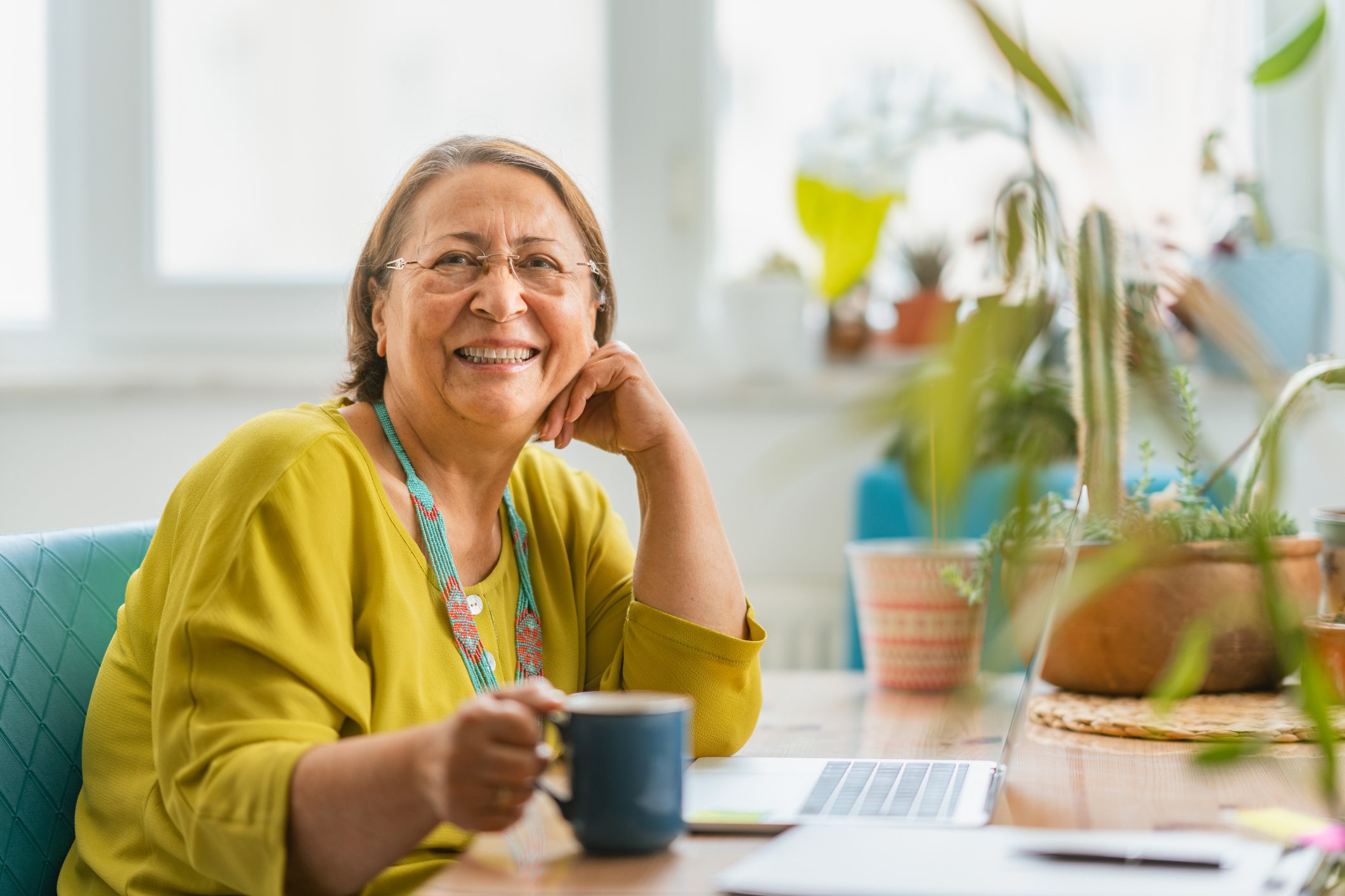 Getty - smiling with cup of coffee tea at desk