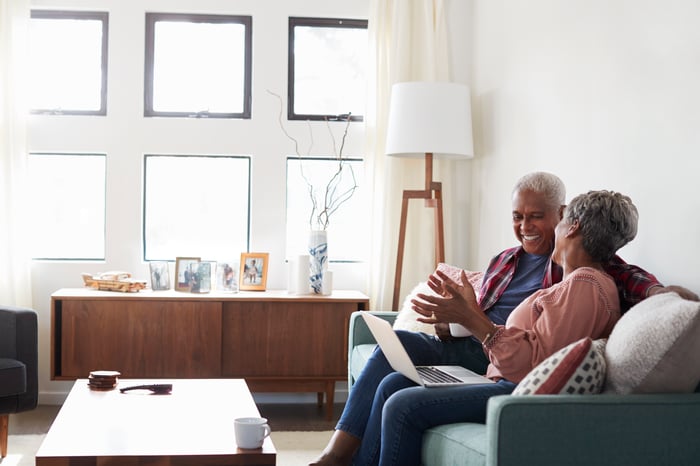 Two people sitting on a couch and smiling.