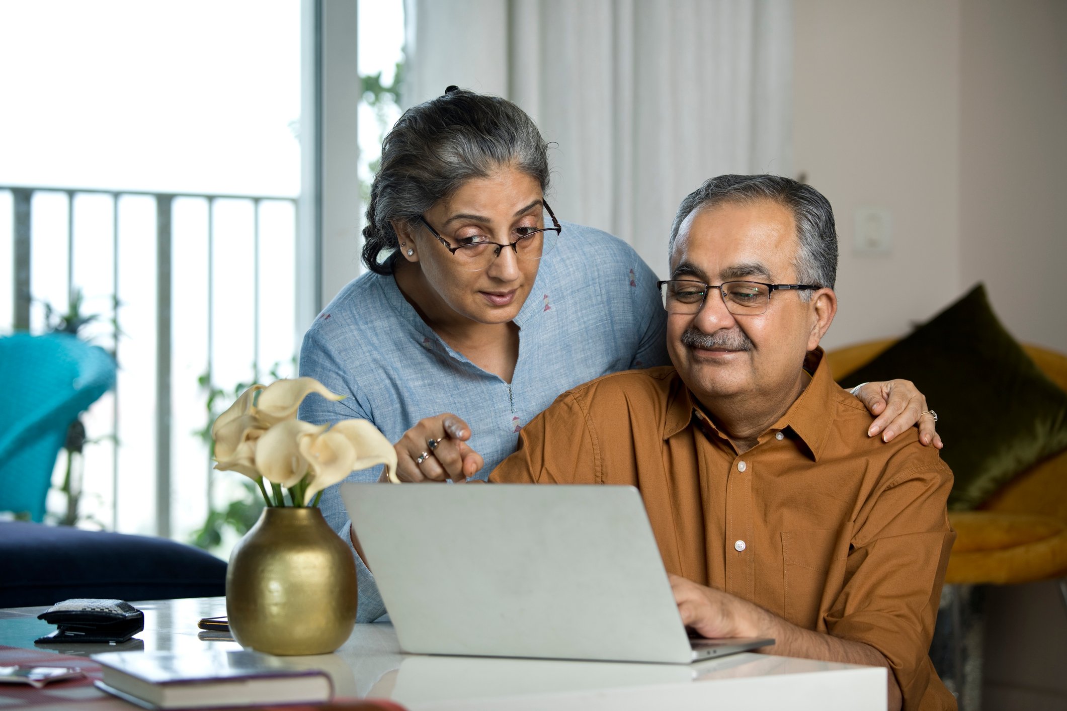 A couple is conferring over an open laptop. 