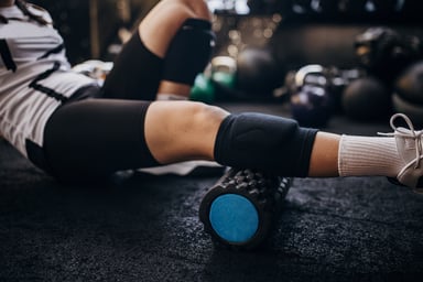 Young woman massaging calf in gym