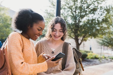 Teen shows friend something on their smart phone