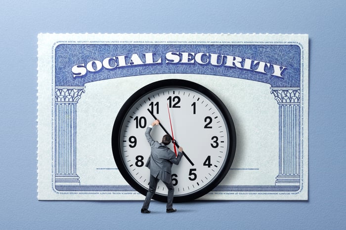 A person pushing the  hands of a clock attached the front of a Social Security card, indicating that time is ticking on benefit cuts.