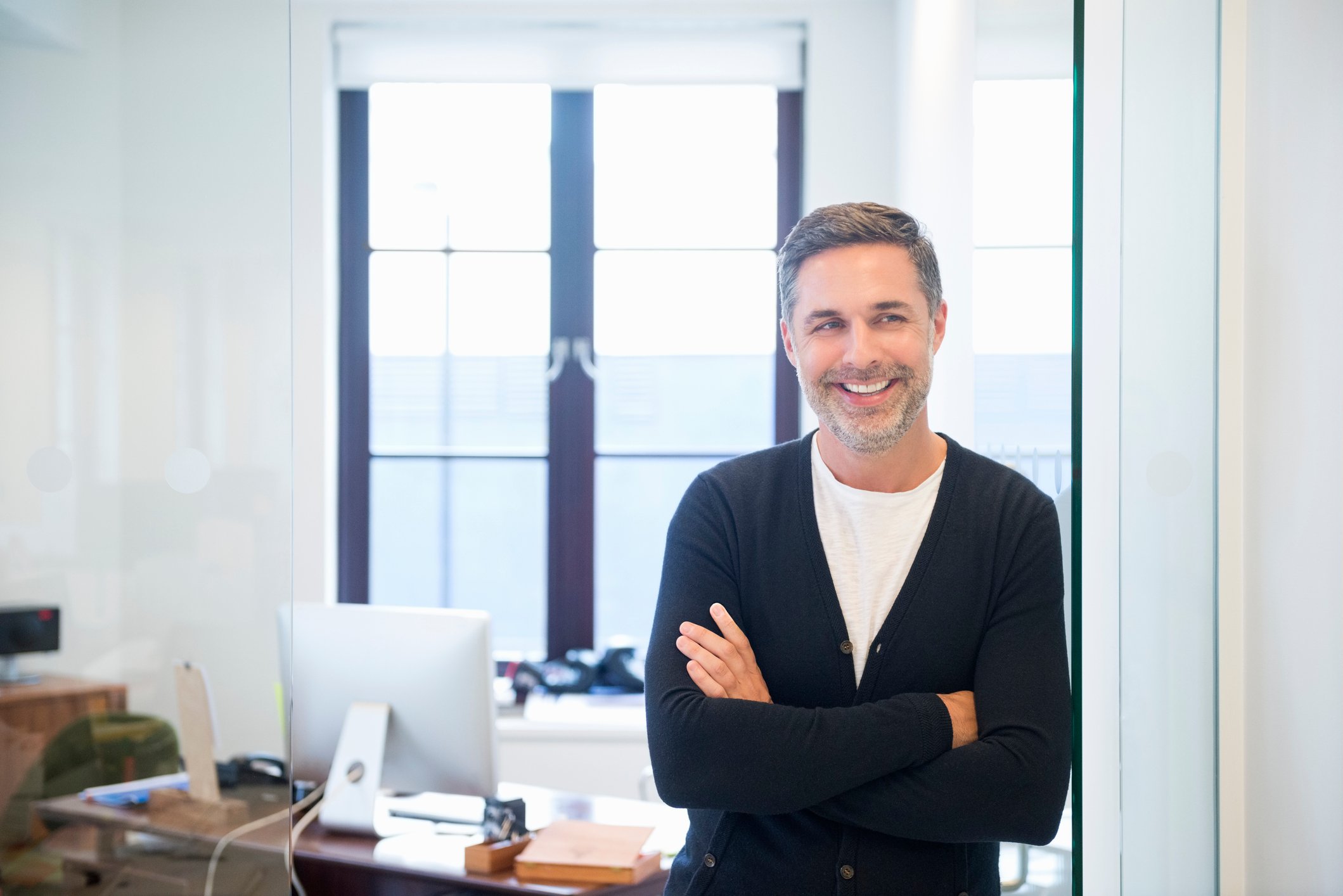 A smiling person standing in front of a desk.