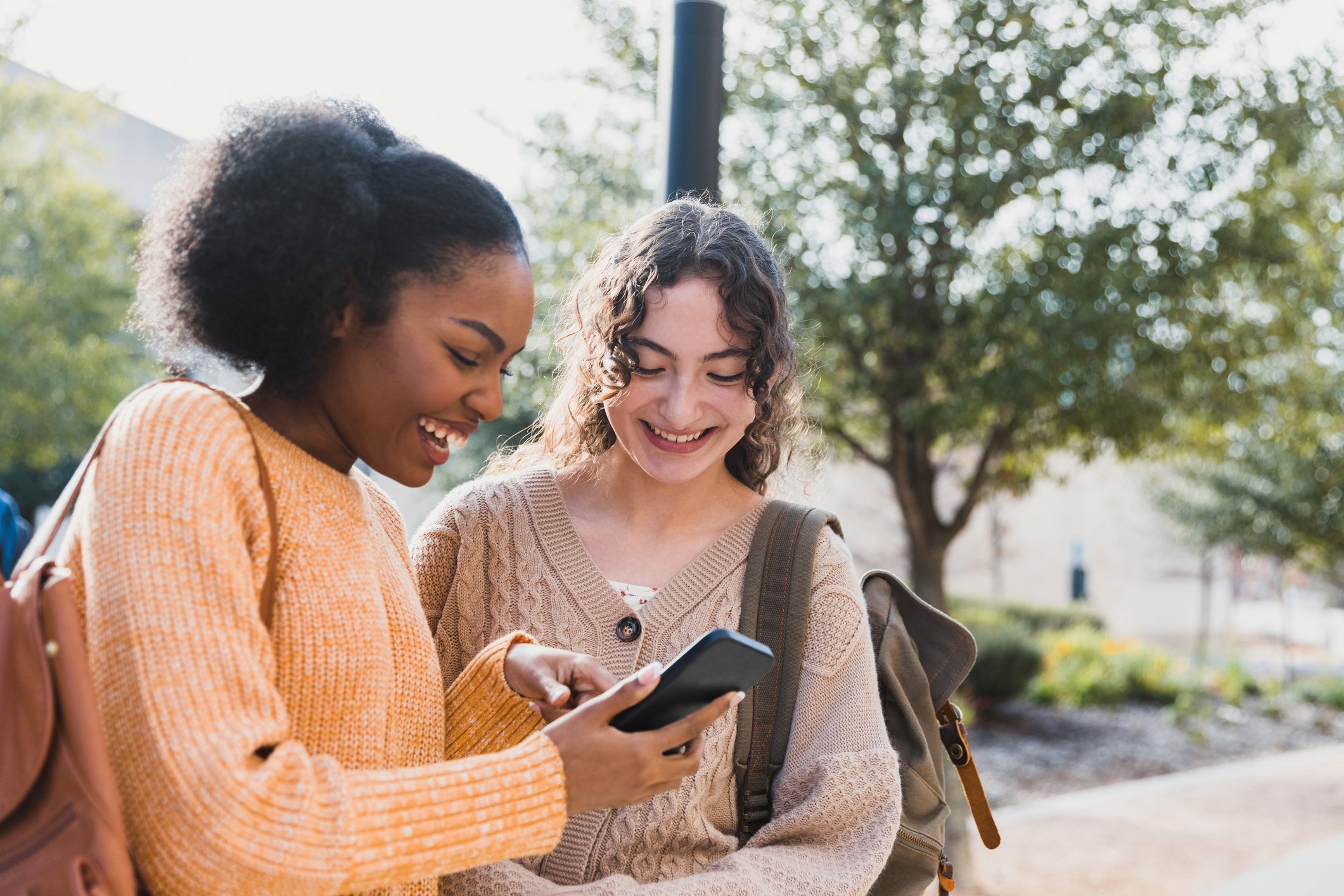 Teen shows friend something on their smart phone