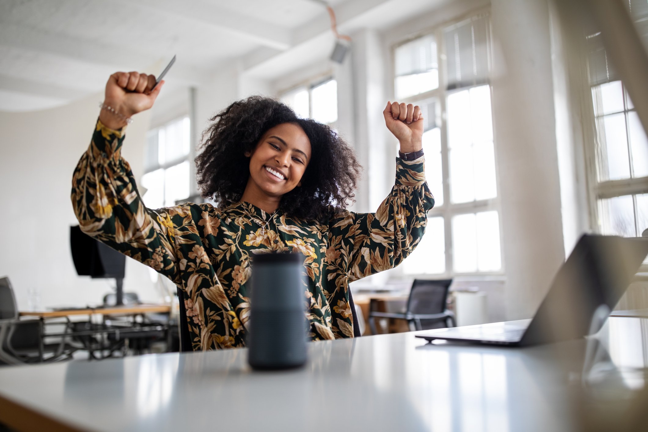 An investor cheers as she sits at her desk.