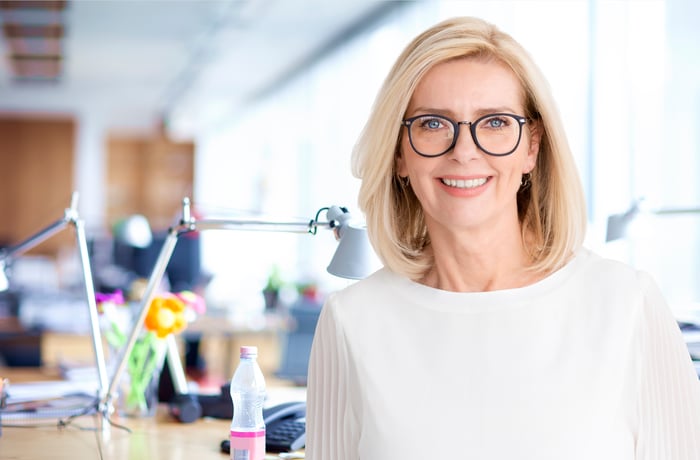 A smiling person in front of a desk.