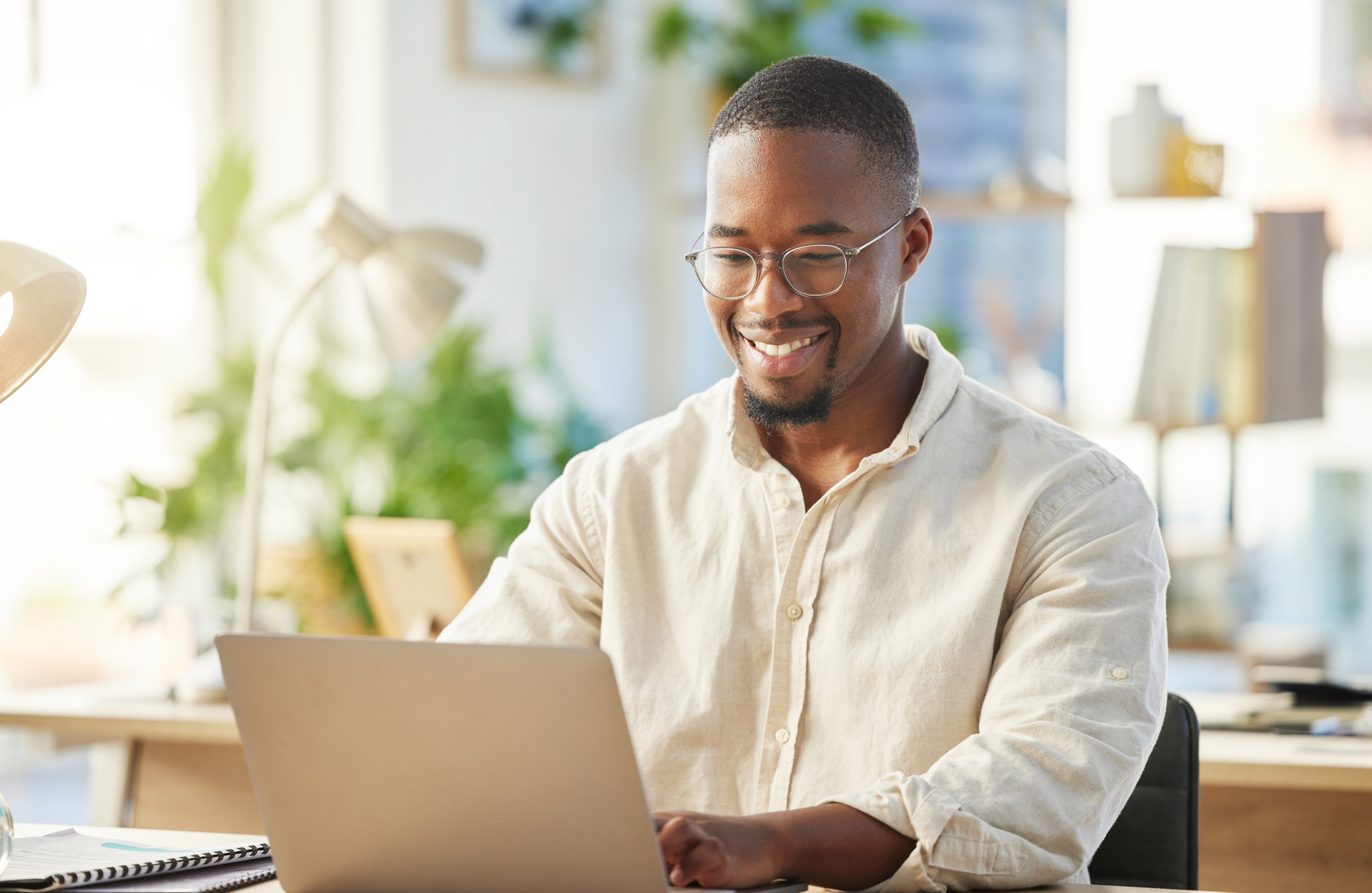 A smiling person at a laptop.