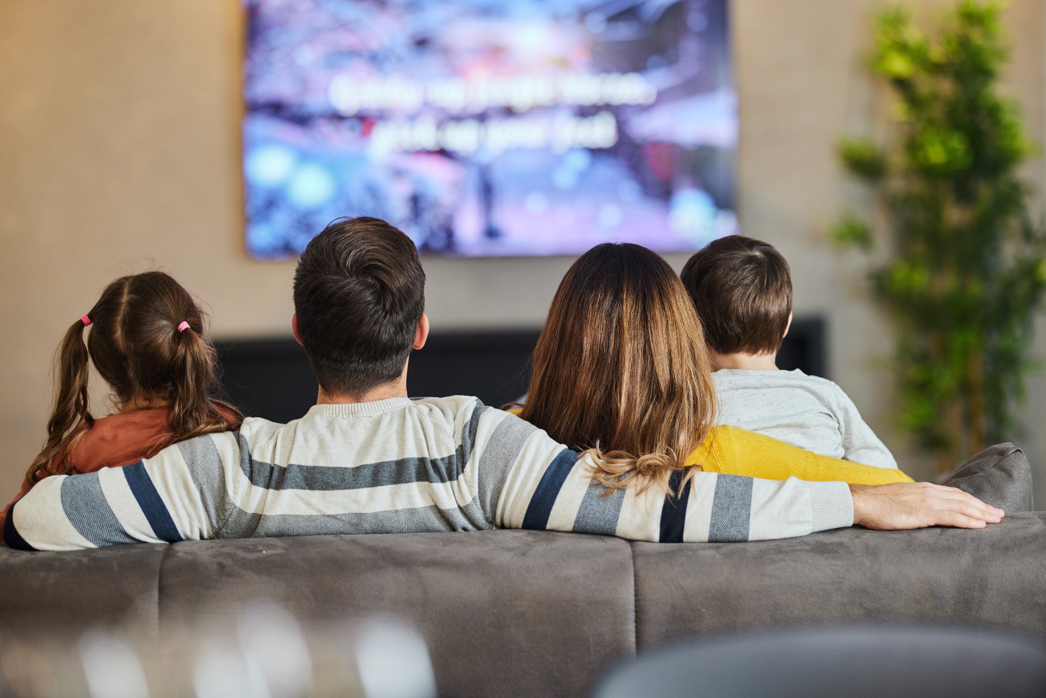 Back view of a family watching TV at home