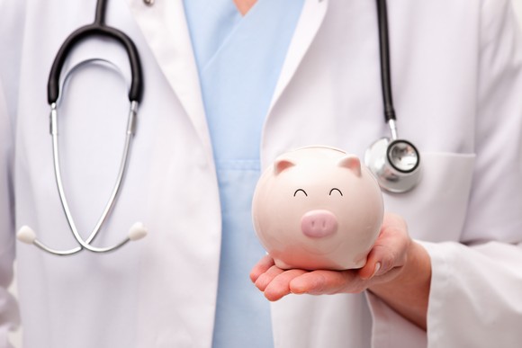 A doctor holding a piggy bank.