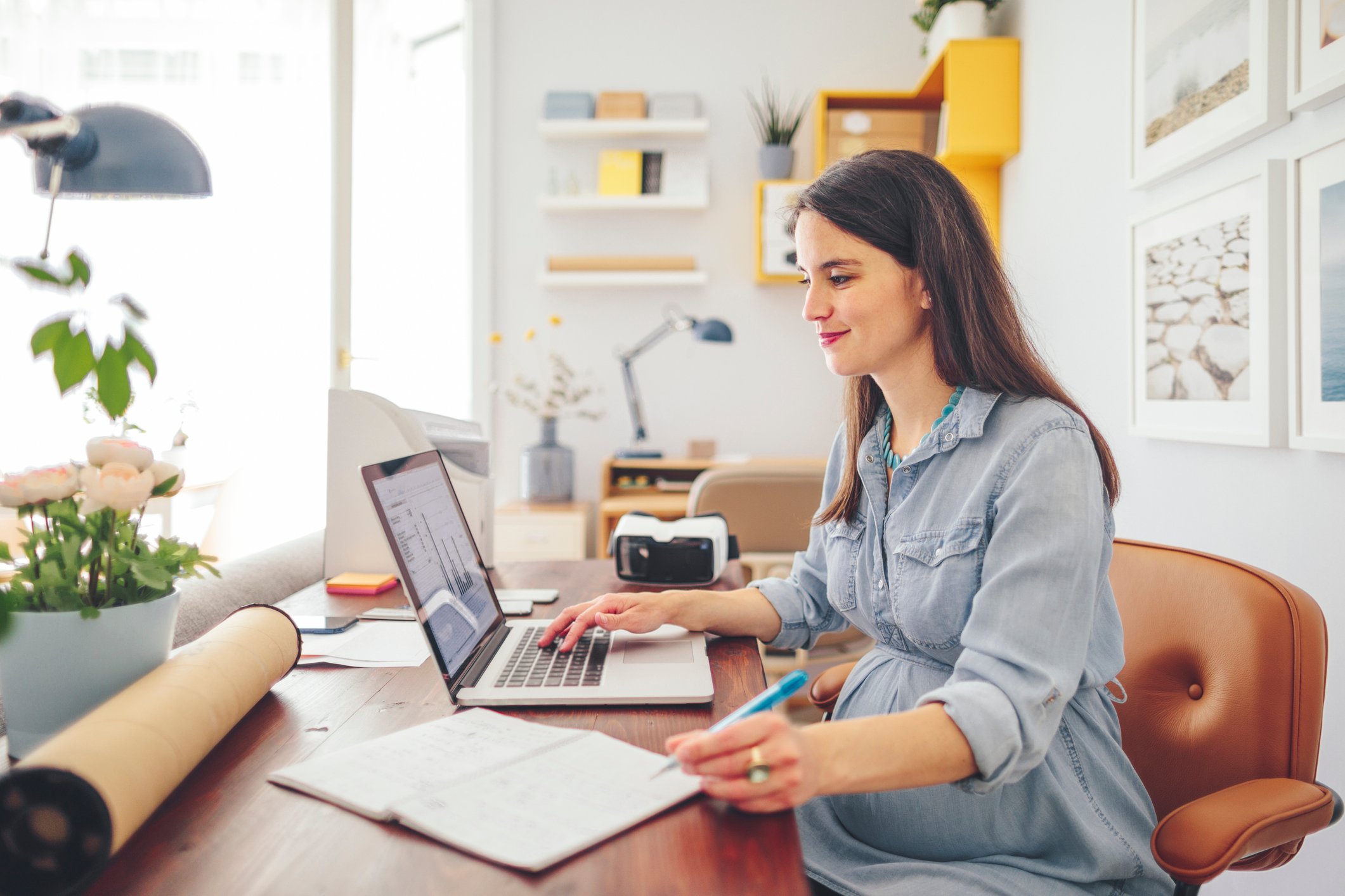 A person sits at a desk looking at a laptop.
