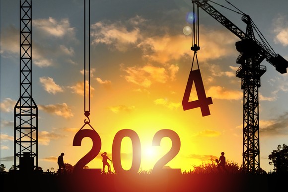 A crane hoisting large numbers 2024 during sunset.