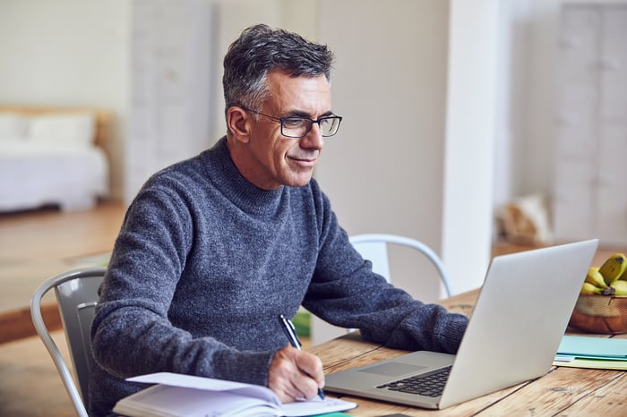 A person taking notes at a laptop.