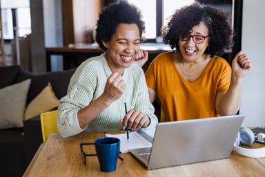 Two people smile as they shop online