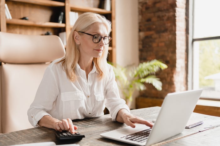 A person using a laptop and calculator.