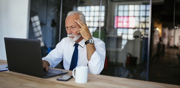 A person in an office looking at a laptop.