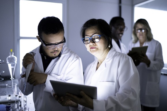 Two researchers study something on a tablet in a lab.