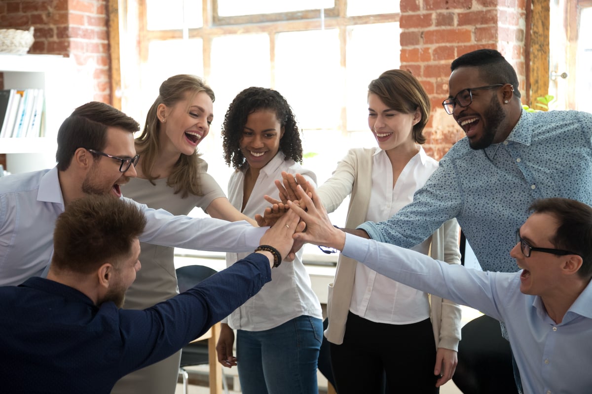 People in an office with their hands together.