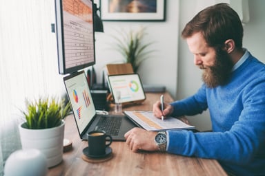 bearded person at desk by computer taking notes (1)