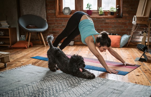 Women Practising Yoga with Dog Beside Her