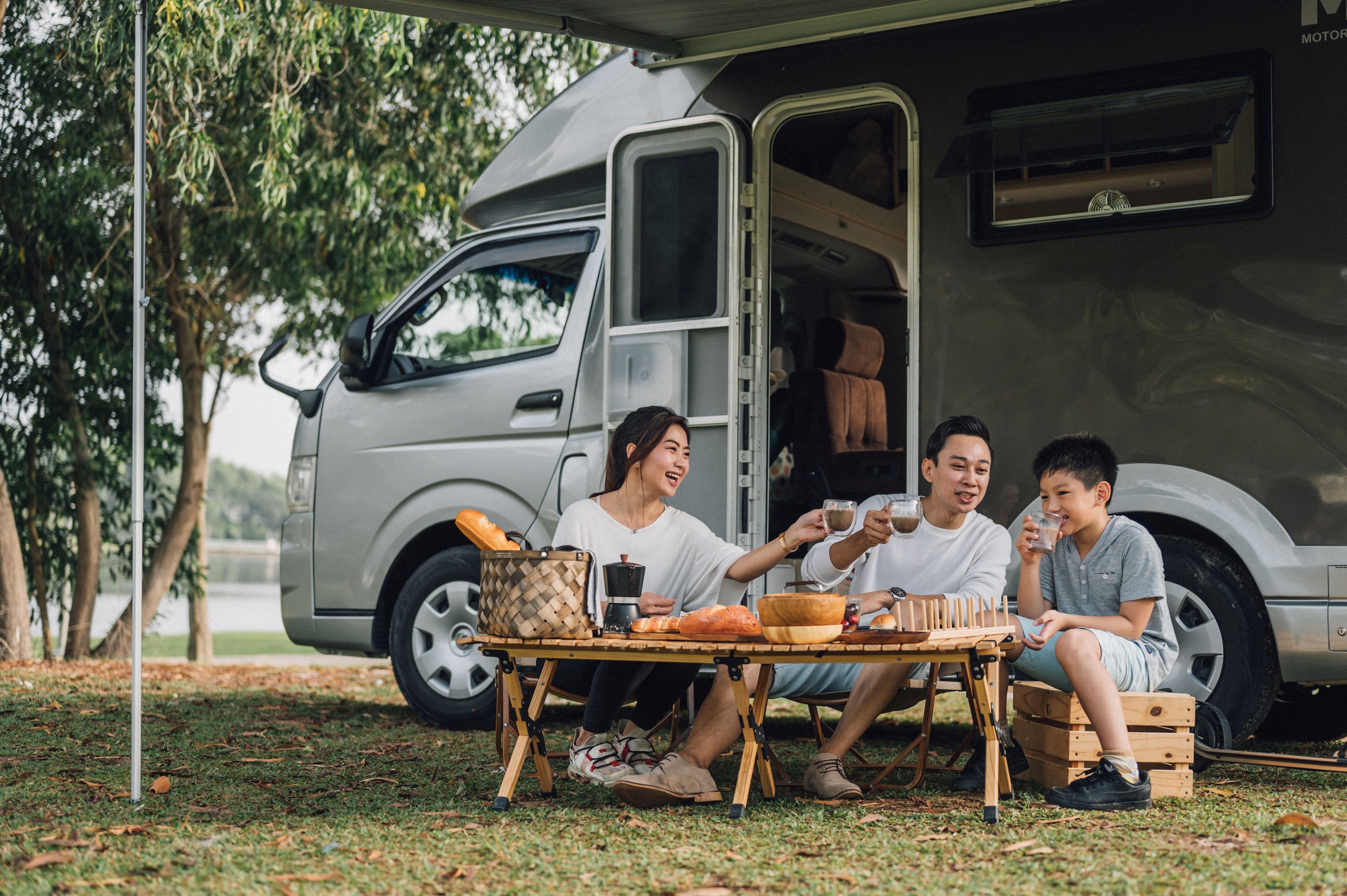 A family at a picnic table outside a camper van.